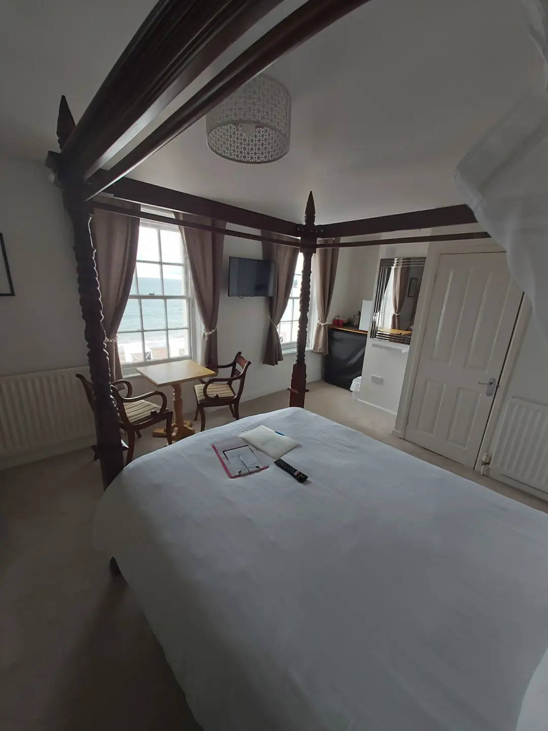 Bright seaside bedroom featuring a four-poster bed and ocean views.