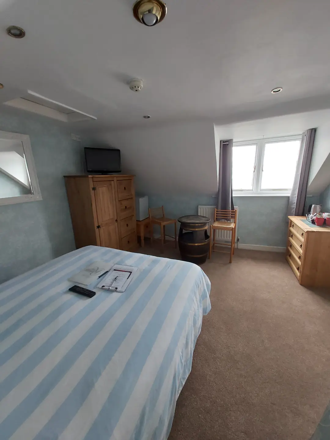 Bright guest bedroom with double bed, wooden furniture and window.