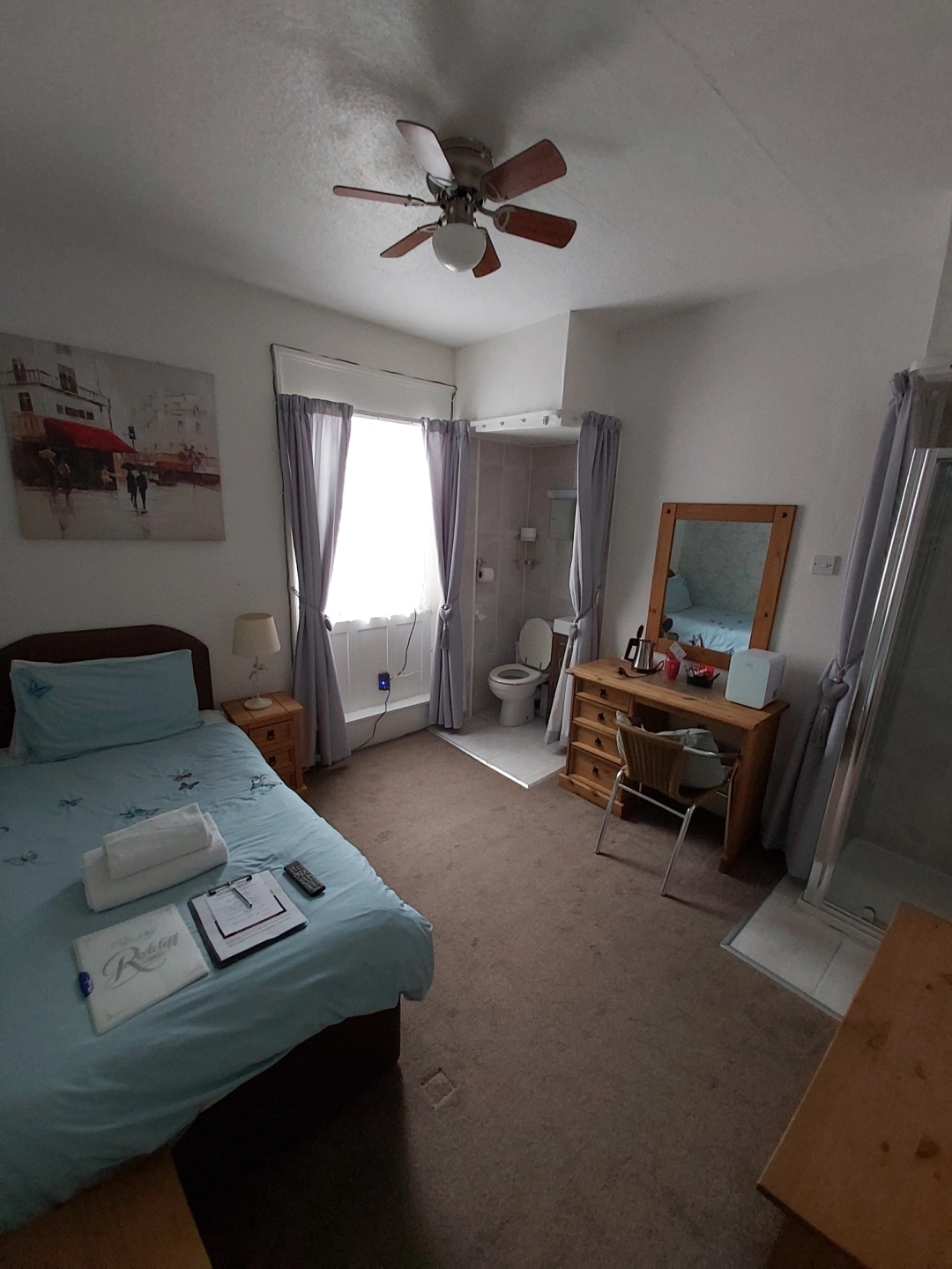 Bright single bedroom with en-suite facilities and wooden dressing table.