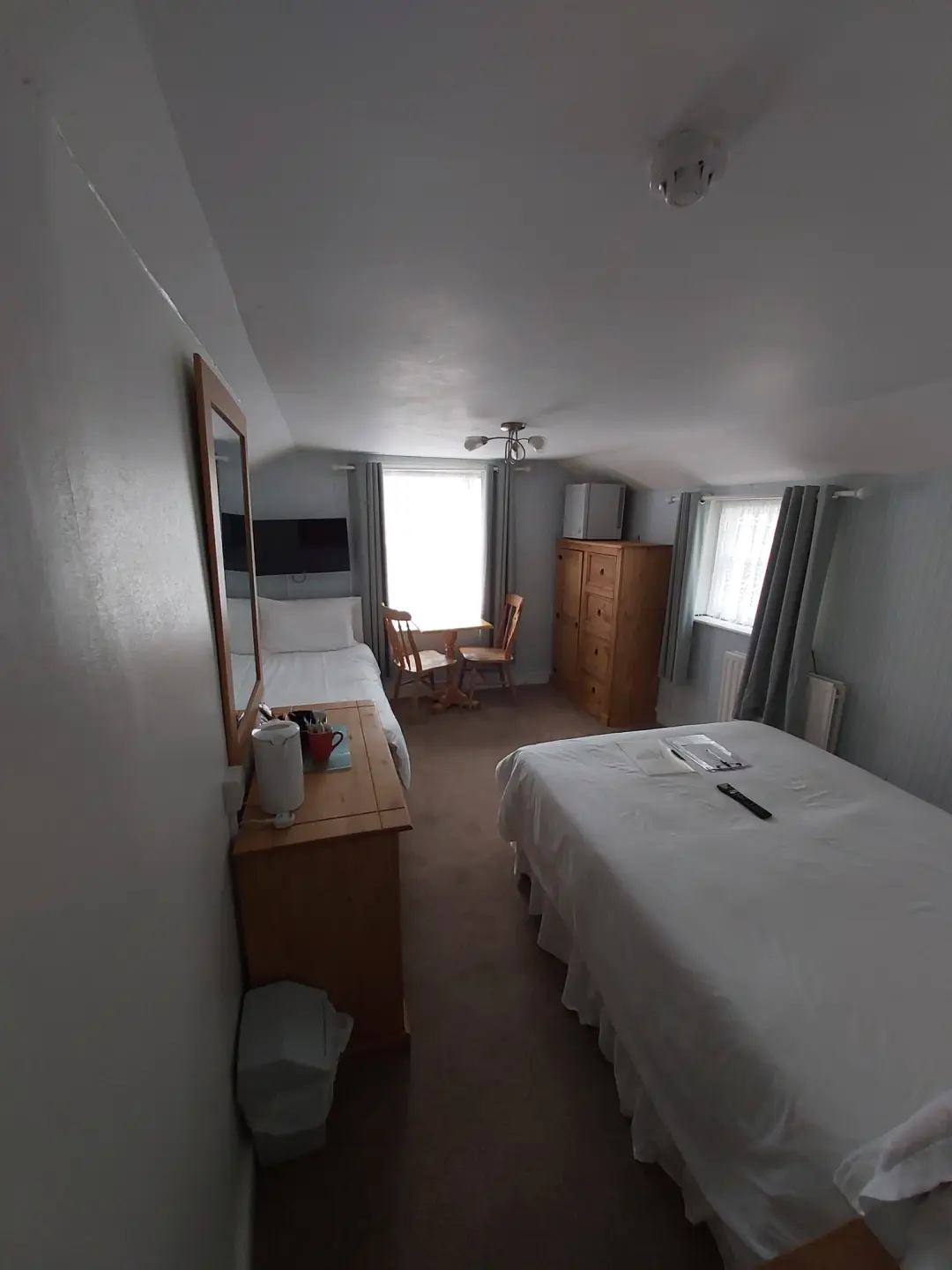Bright guest bedroom with double bed, seating and wooden furniture.