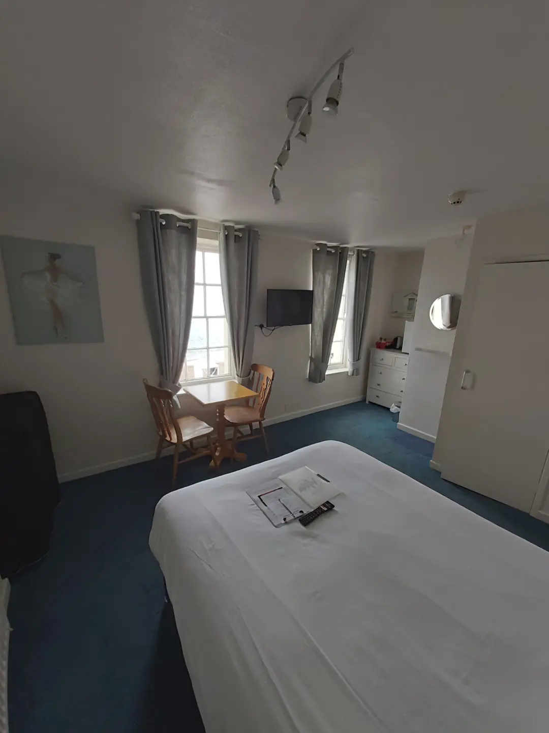 Bright guest room with bed, seating, television and large windows.
